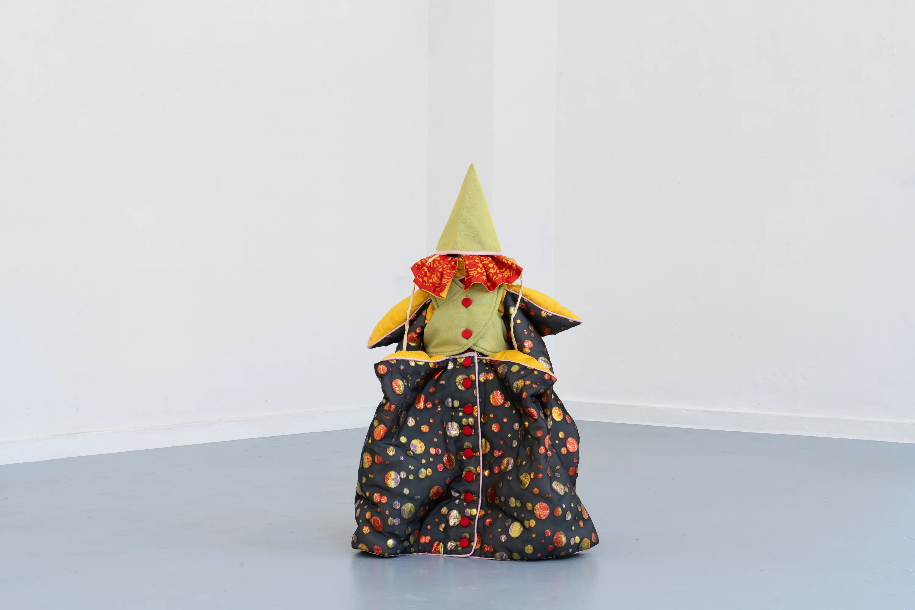 Elle est nue sous ses cheveux, 2026. argile rouge crue, coques de grillage et plâtre, diffusion sonore, costume d'enfant. Photo © Margot Anquez-Bariseau