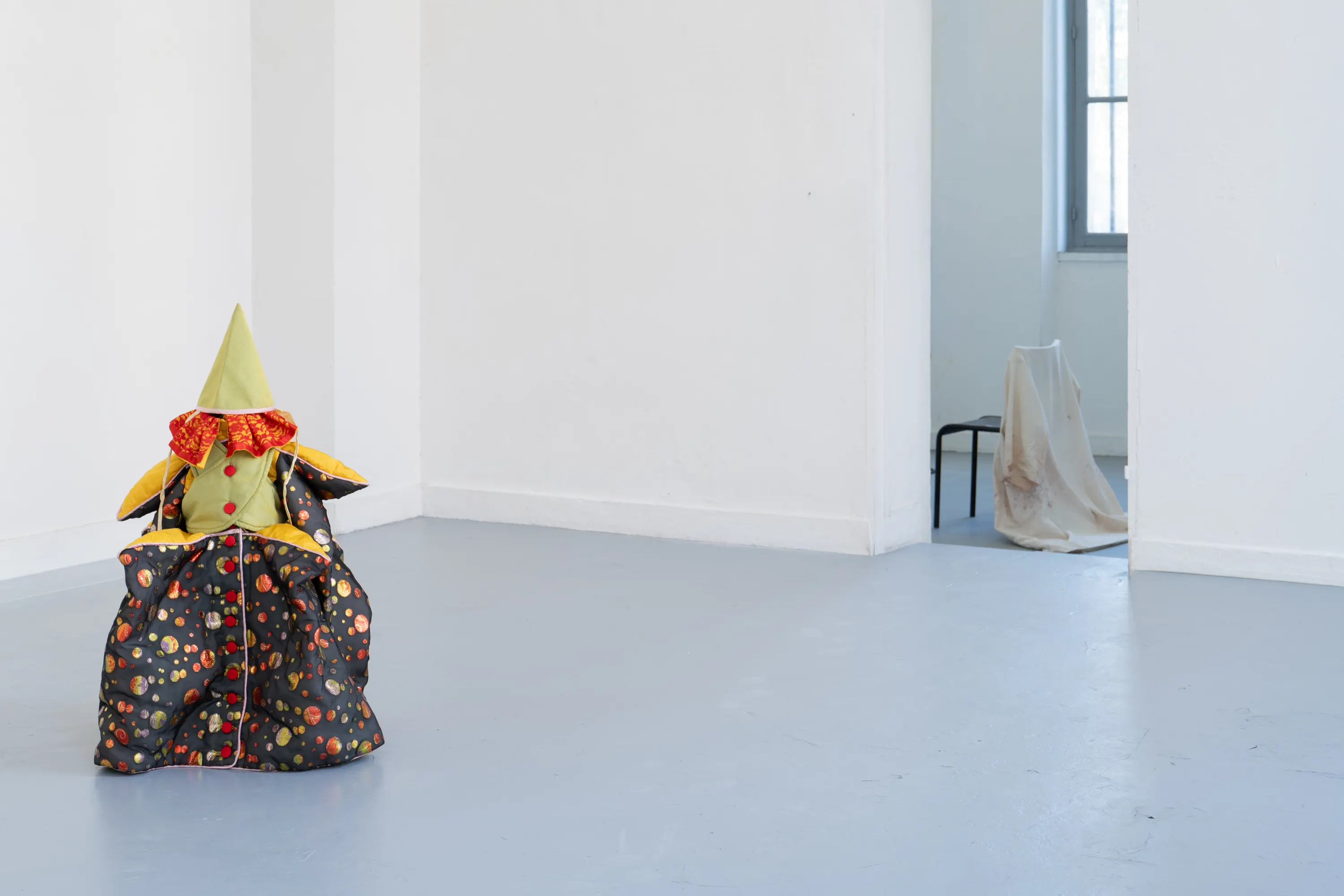Elle est nue sous ses cheveux, 2026. argile rouge crue, coques de grillage et plâtre, diffusion sonore, costume d'enfant. Photo © Margot Anquez-Bariseau